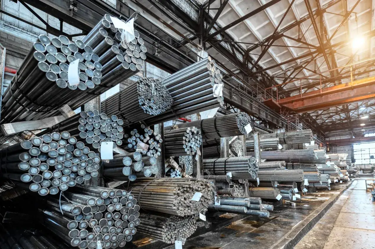 Silos stali zbrojeniowej w magazynie. Wiele wiązek prętów stalowych ułożonych na półkach, gotowych do wysyłki. Cena stali zbrojeniowej zależy od wielu czynników.
