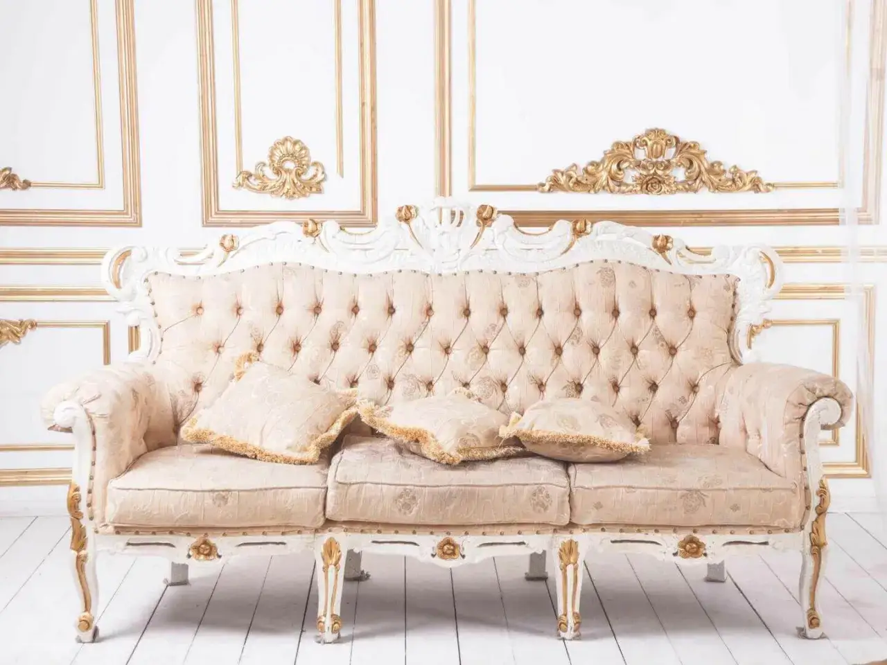 Ein prunkvolles Sofa mit einem zarten **muster paisley**-Stoff und goldverzierten Elementen, vor einer Wand mit opulenten Goldornamenten.