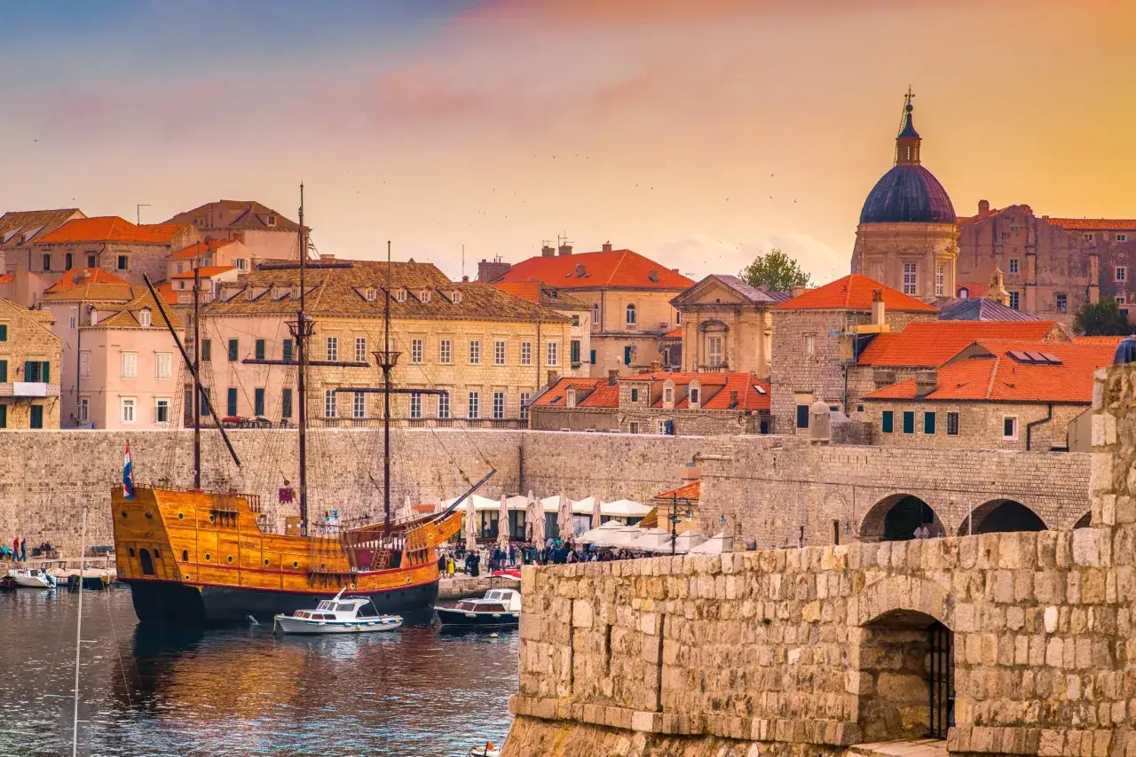 Stare miasto w Dubrowniku z kamiennymi murami, portem i zabytkowym żaglowcem. Czy to Split czy Dubrownik? To na pewno Dubrownik!