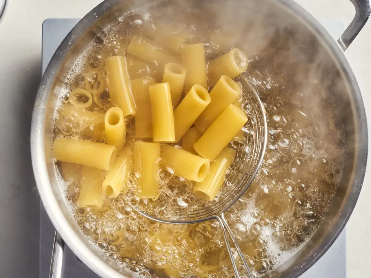 Kiedy wrzucić makaron do wody? Gdy woda mocno wrze, a bąbelki unoszą się ku g&oacute;rze. Makaron rigatoni gotuje się w bulgoczącej wodzie.