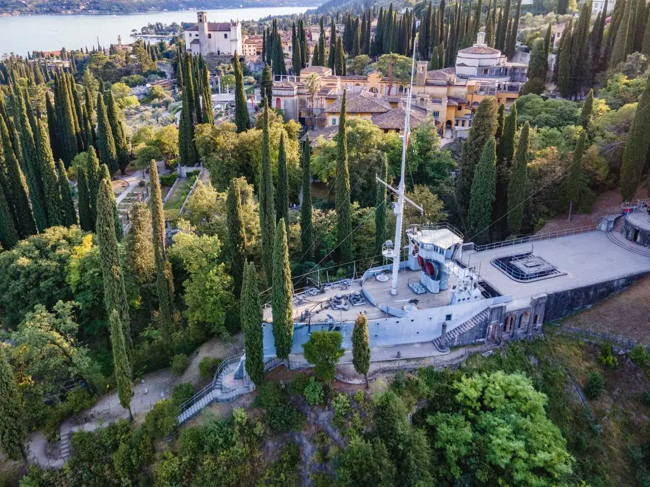 Un'imponente nave ancorata tra cipressi secolari, un invito a visitare il Vittoriale. Un luogo unico che incanta con la sua storia e la sua vista sul lago.