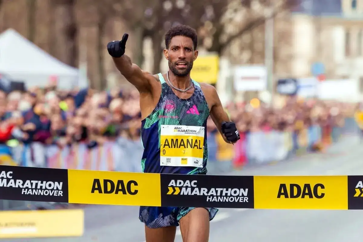 Läufer Amanal überquert die Ziellinie des ADAC Marathon Hannover, Daumen hoch für gute Halbmarathon Zeiten.