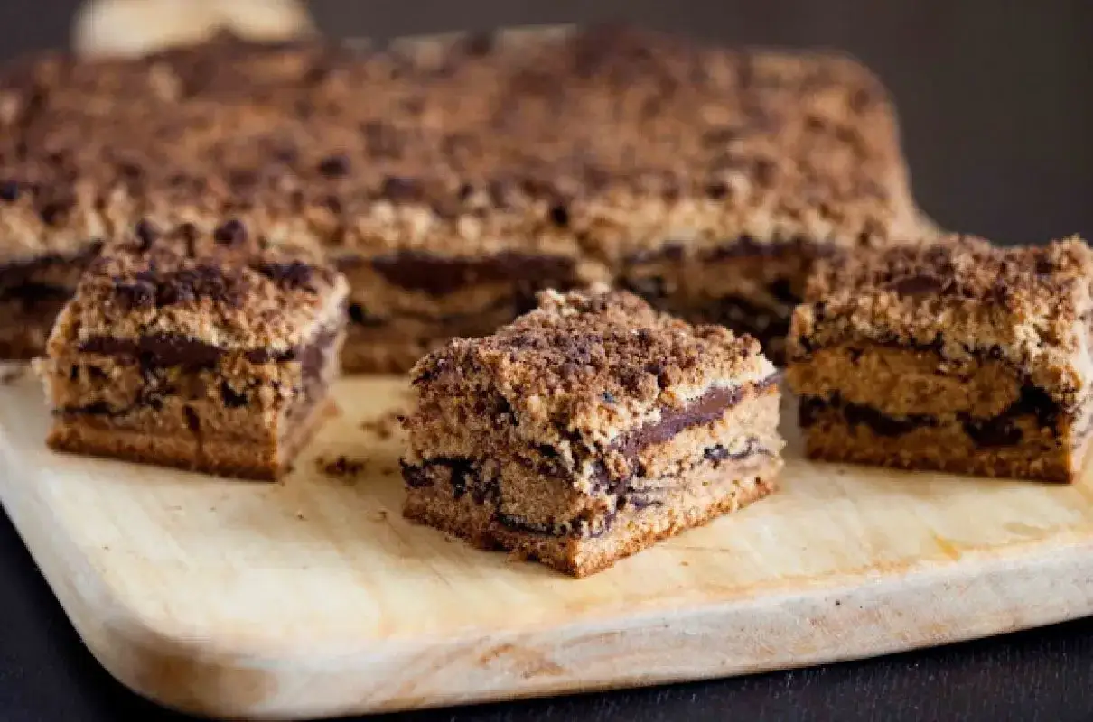 Pyszny brownie z masłem orzechowym, pokrojone na kwadraty, z chrupiącą kruszonką na wierzchu, ułożone na drewnianej desce.