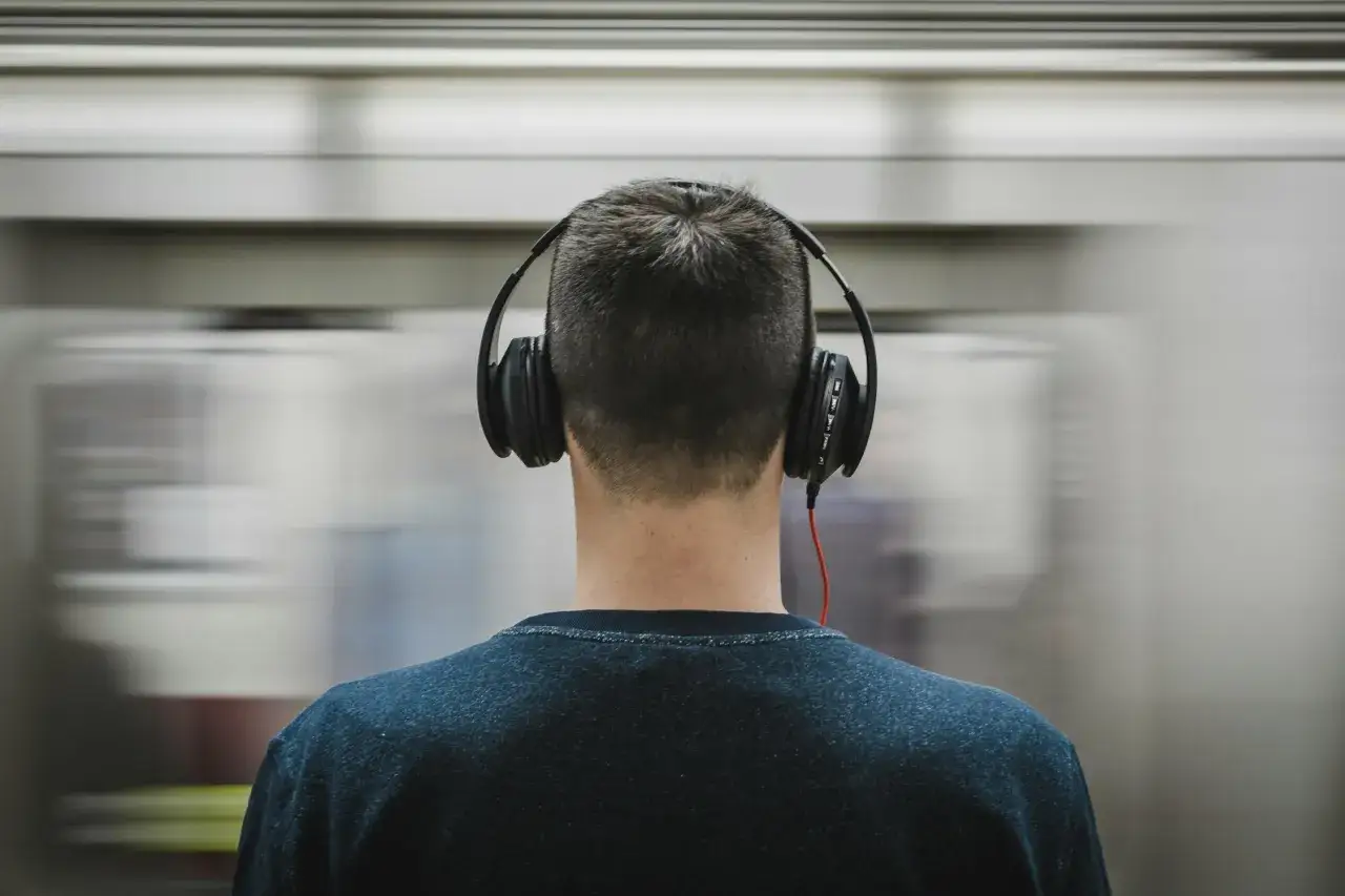 Mann mit Kopfhörern hört gruselige Musik, während ein Zug vorbeirast.