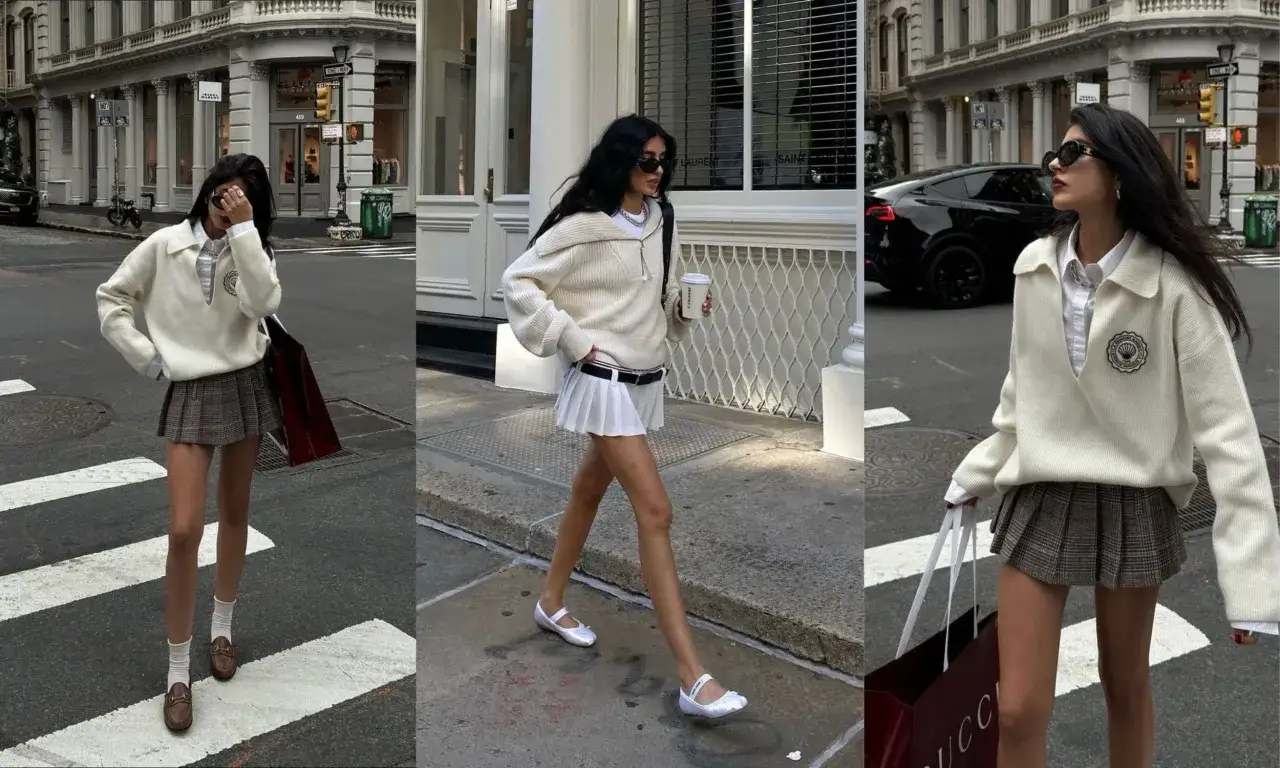 Une jeune femme arbore un look preppy avec un pull blanc, une jupe pliss&eacute;e &agrave; carreaux et des mocassins. Elle se prom&egrave;ne en ville, un caf&eacute; &agrave; la main.