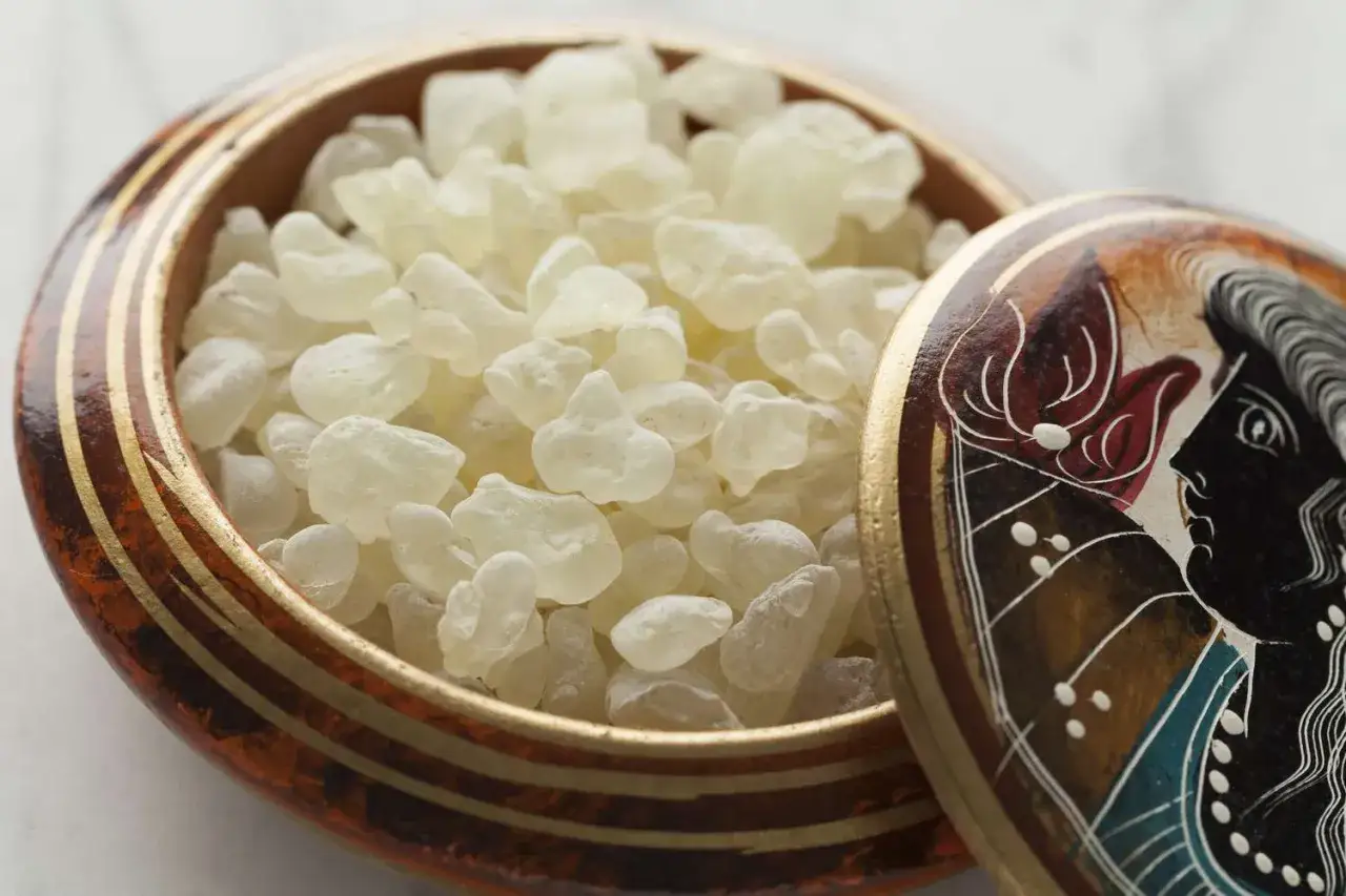 Resina de mastic gum para que sirve: peque&ntilde;os cristales blancos en un cuenco decorado con un perfil griego.