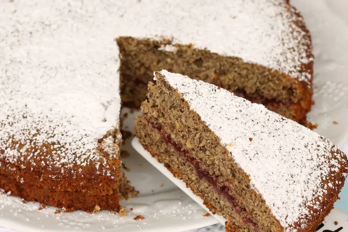 Torta di grano saraceno trentino, soffice e profumata, con un ripieno di confettura di frutti rossi, cosparsa di zucchero a velo.