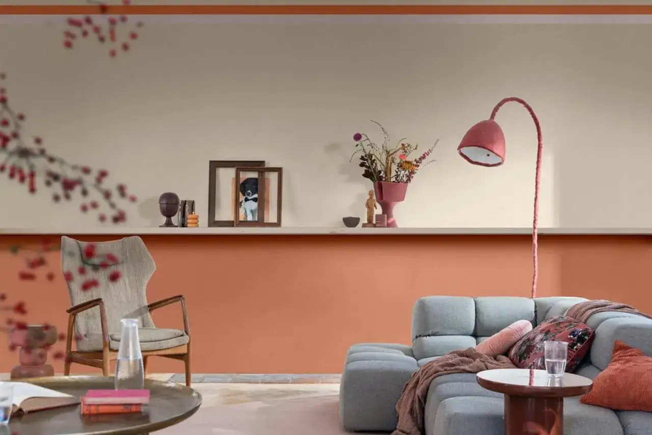 Soggiorno con pareti dipinte particolari: la parte inferiore &egrave; color terracotta, quella superiore color crema. Arredamento moderno con divano grigio e poltrona.