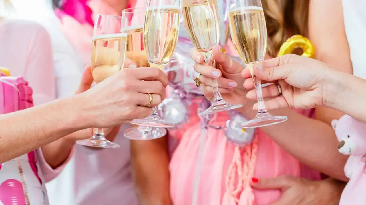 Frauen stoßen mit Gläsern an, die mit alkoholfreiem Sekt gefüllt sind. Eine schwangere Frau feiert mit ihren Freundinnen.