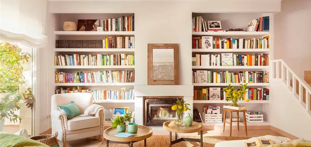 Estanterías llenas de libros que hay que leer antes de morir, un sillón cómodo y una chimenea invitan a la lectura en este acogedor salón.