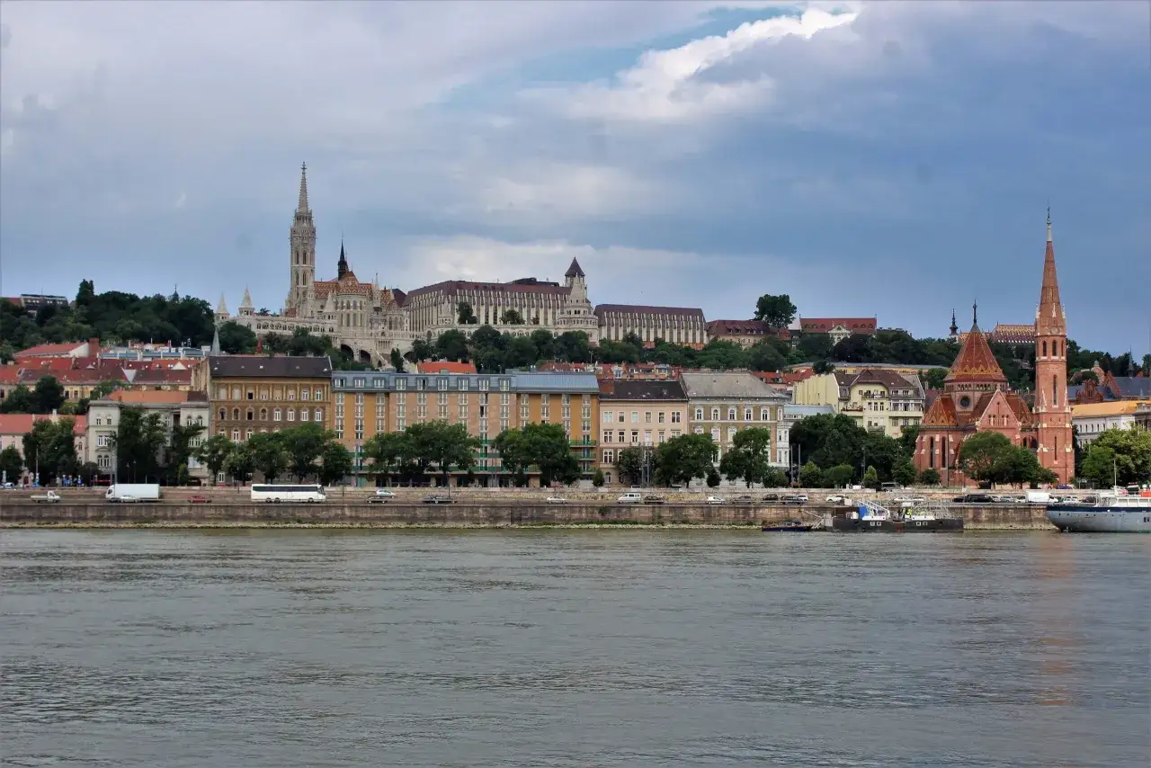 Widok na wzgórze zamkowe w Budapeszcie z Dunaju, z widocznymi kościołem Macieja i budynkami na zboczu.