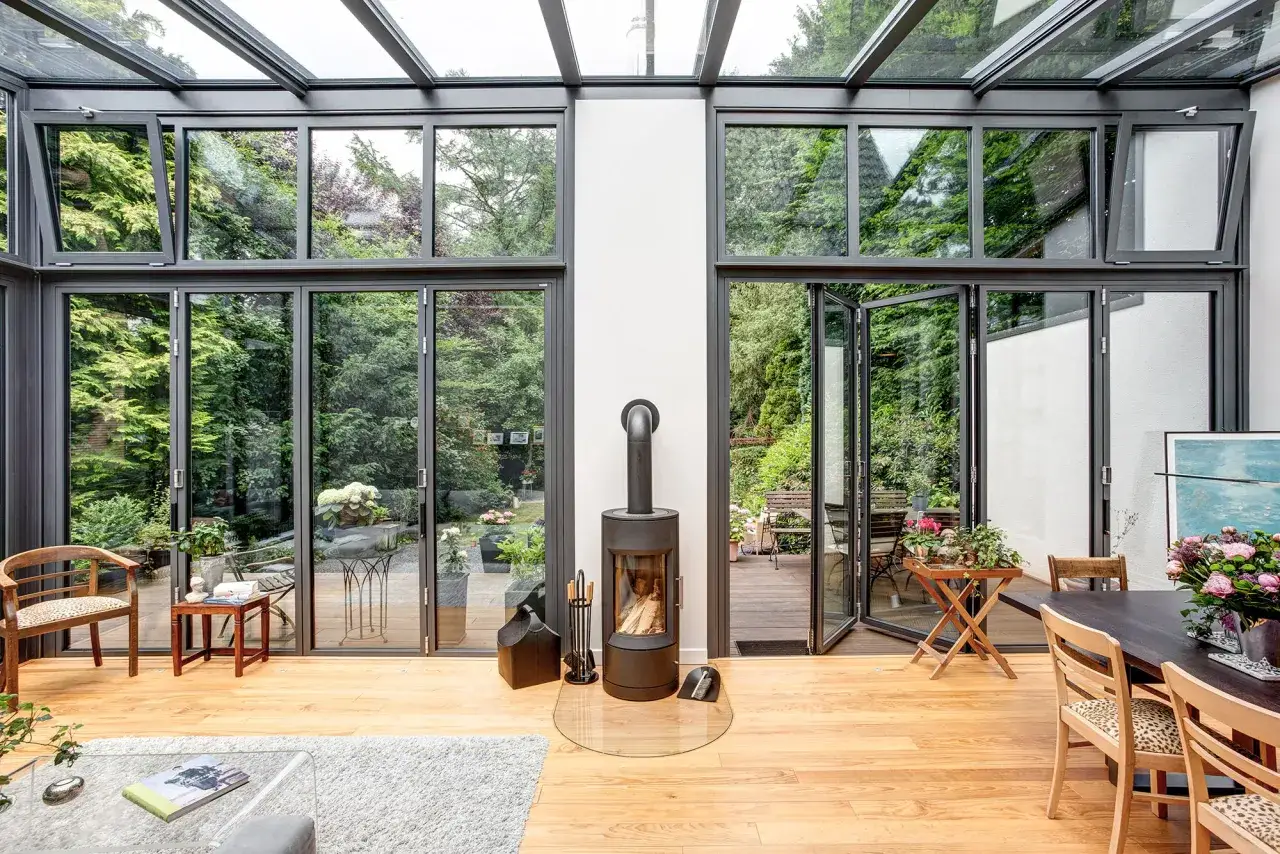 Ein moderner Wintergarten mit Glasdach und gro&szlig;en Fenstern l&auml;dt zum Entspannen ein. Ein Kamin sorgt f&uuml;r Gem&uuml;tlichkeit. Der Anbau Wintergarten verbindet Wohnraum und Natur.