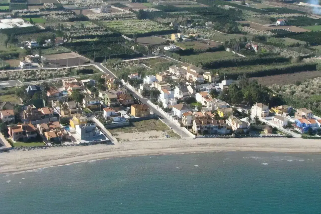 Blick &uuml;ber den Cullera Strand mit bunten H&auml;usern und Feldern im Hintergrund.