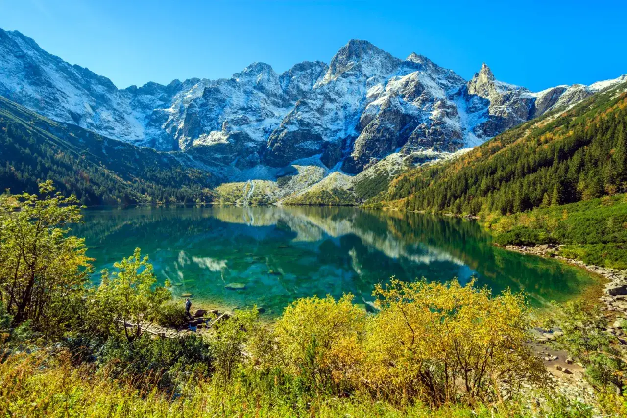 Piękne Morskie Oko, gdzie można by pojechać rowerem, otoczone jesiennymi lasami i ośnieżonymi szczytami Tatr.