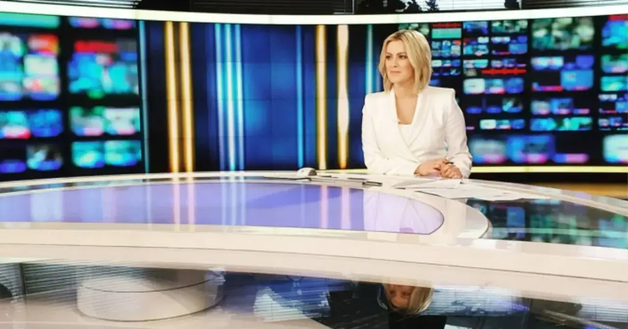 Justyna Kosela, znana prezenterka, siedzi przy stole w studiu telewizyjnym. Jej data urodzenia jest tajemnicą.