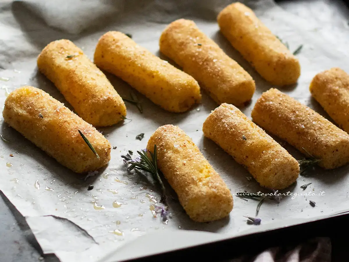 Crocchette di patate al forno dorate e croccanti, pronte per essere gustate. Profumate con rosmarino fresco.