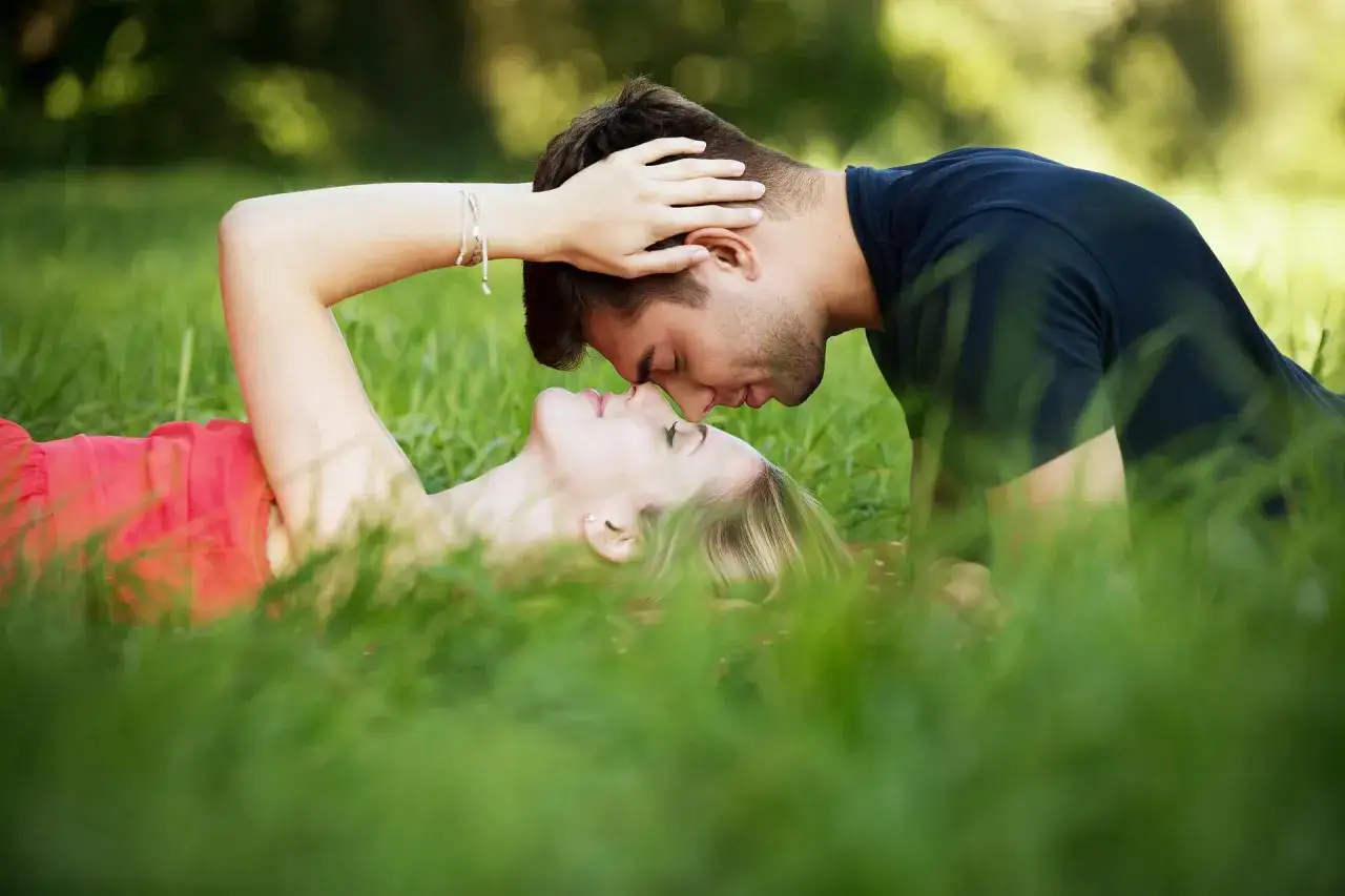 Coppia in un prato, un uomo e una donna si baciano dolcemente. Un momento di intimo sesso a coppia, immersi nella natura.