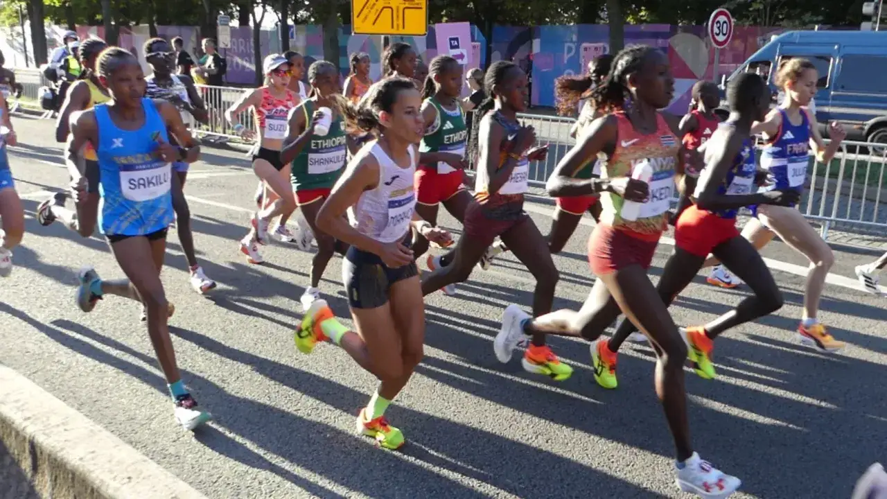 Kobiety biegną w maratonie, pokazując determinację w dążeniu do celu. Każdy krok przybliża je do mety, a ich wysiłek jest dowodem na to, jak przebiec maraton.