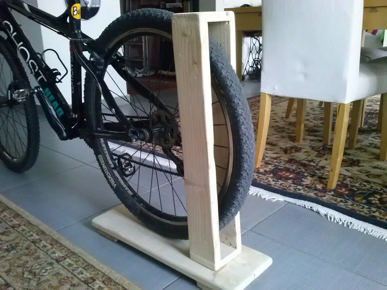 Un vélo est placé dans un support en bois fait maison, idéal pour fabriquer un porte vélo de soute.
