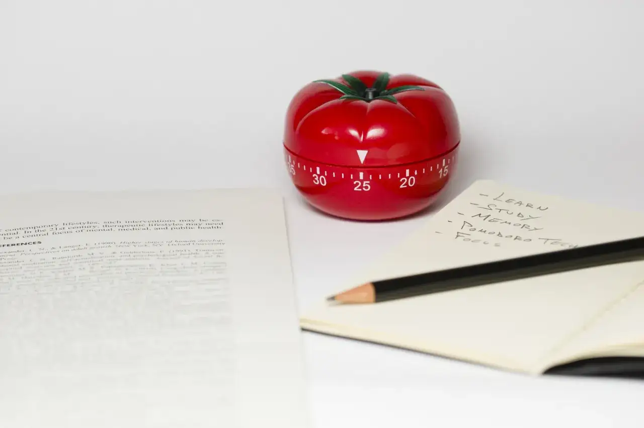 Osoba ucząca się z zegarem Pomodoro i notatkami