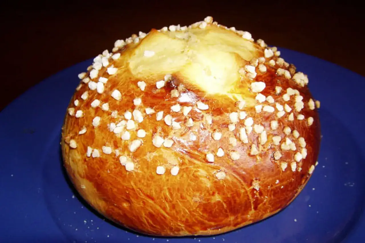 Mouna pied noir dorée, parsemée de sucre perlé, prête à être dégustée. Une recette traditionnelle pleine de saveurs.