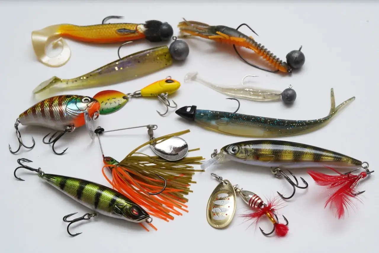 Vielfältige Kunstköder für das Barschangeln im Winter: Gummifische, Wobbler und Spinner in verschiedenen Farben und Formen.