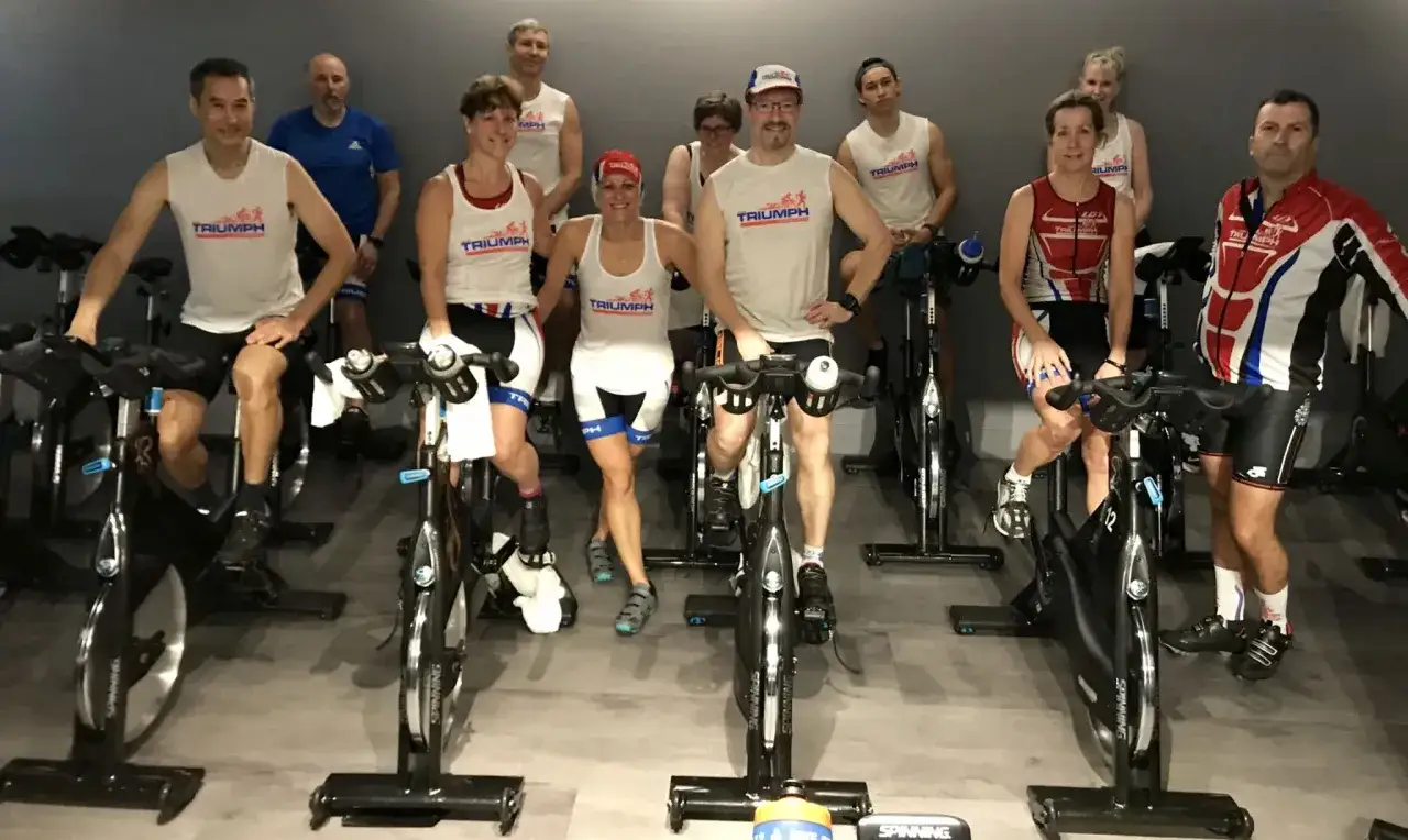 Gruppe von Menschen, die auf Spinning-Rädern trainieren. Sie tragen Sportkleidung und lächeln.