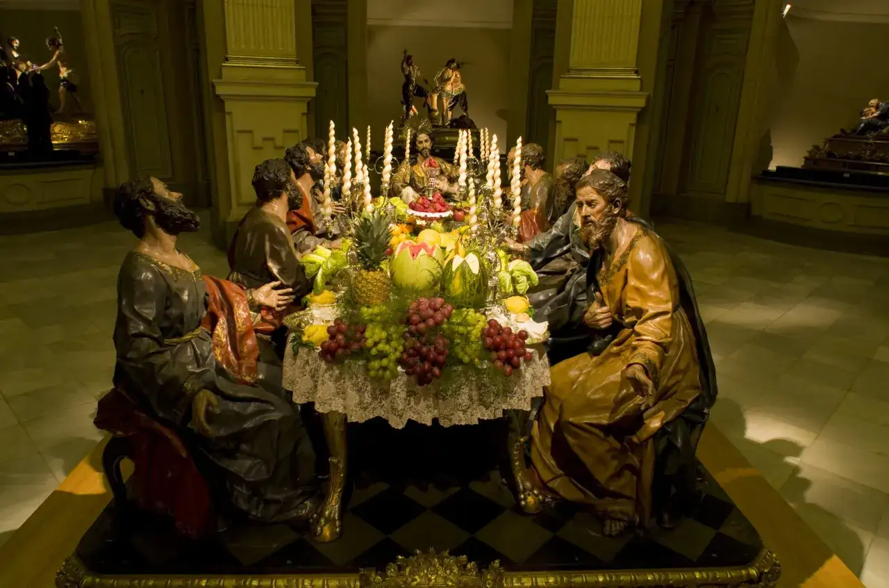Escena de la Última Cena, con Jesús y los apóstoles alrededor de una mesa cargada de frutas y velas. Una representación conmovedora para las procesiones de Semana Santa y Viernes Santo.