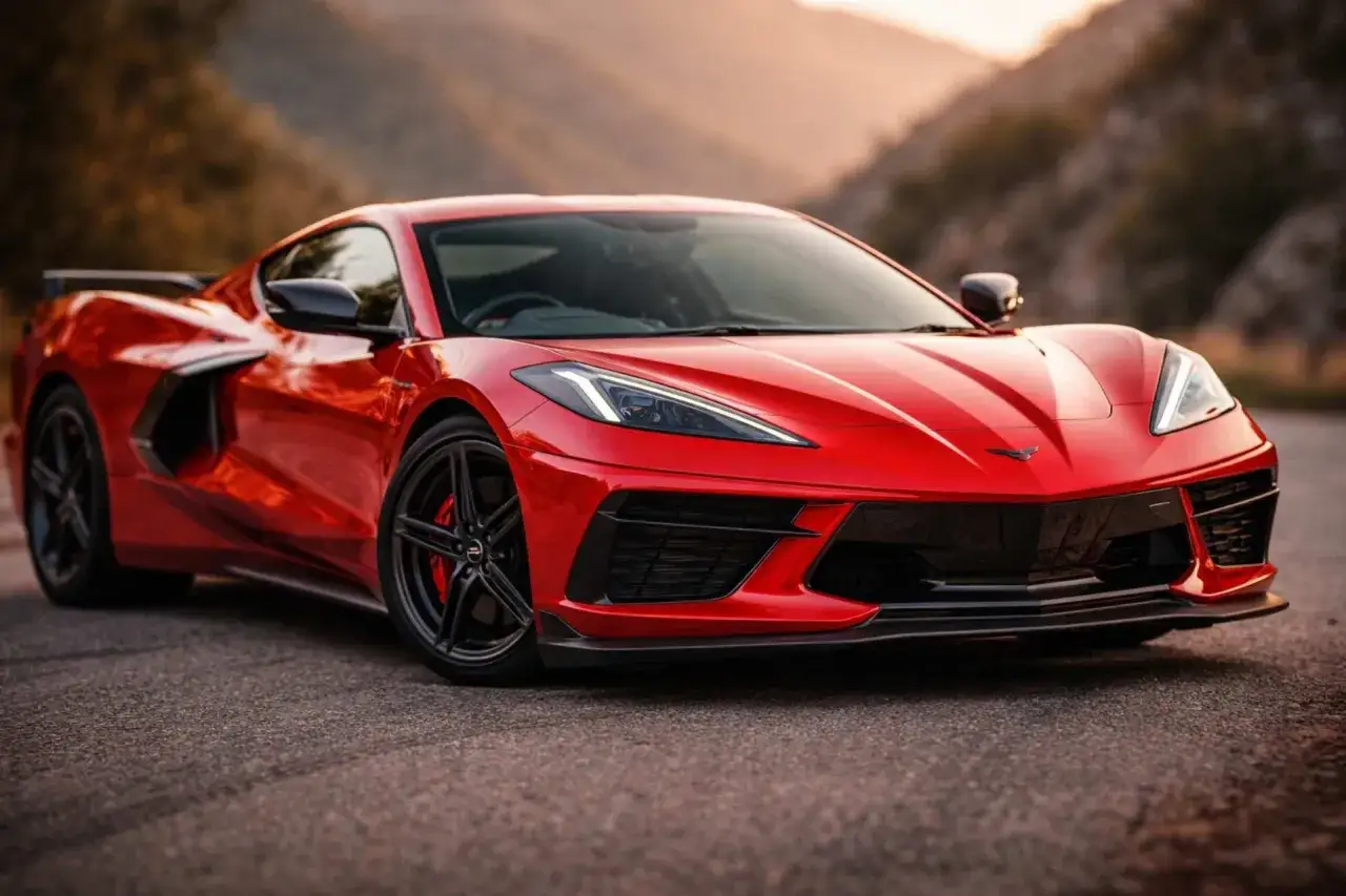 Czerwony Chevrolet Corvette C8, jeden z najnowszych modeli, prezentuje się dynamicznie na tle górskiego krajobrazu.