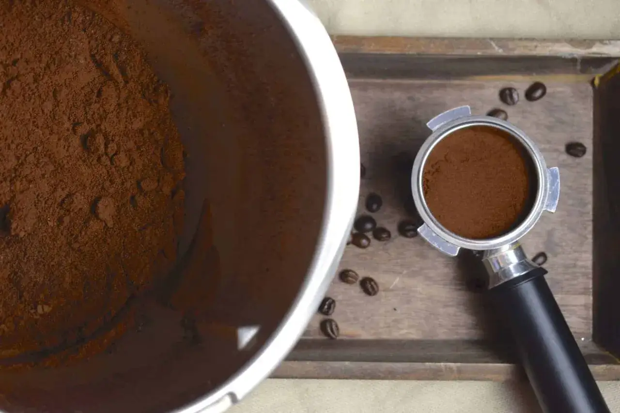 Frisch gemahlene Kaffeebohnen im Thermomix-Behälter und im Siebträger. Der Duft von frisch gemahlenem Kaffee liegt in der Luft.