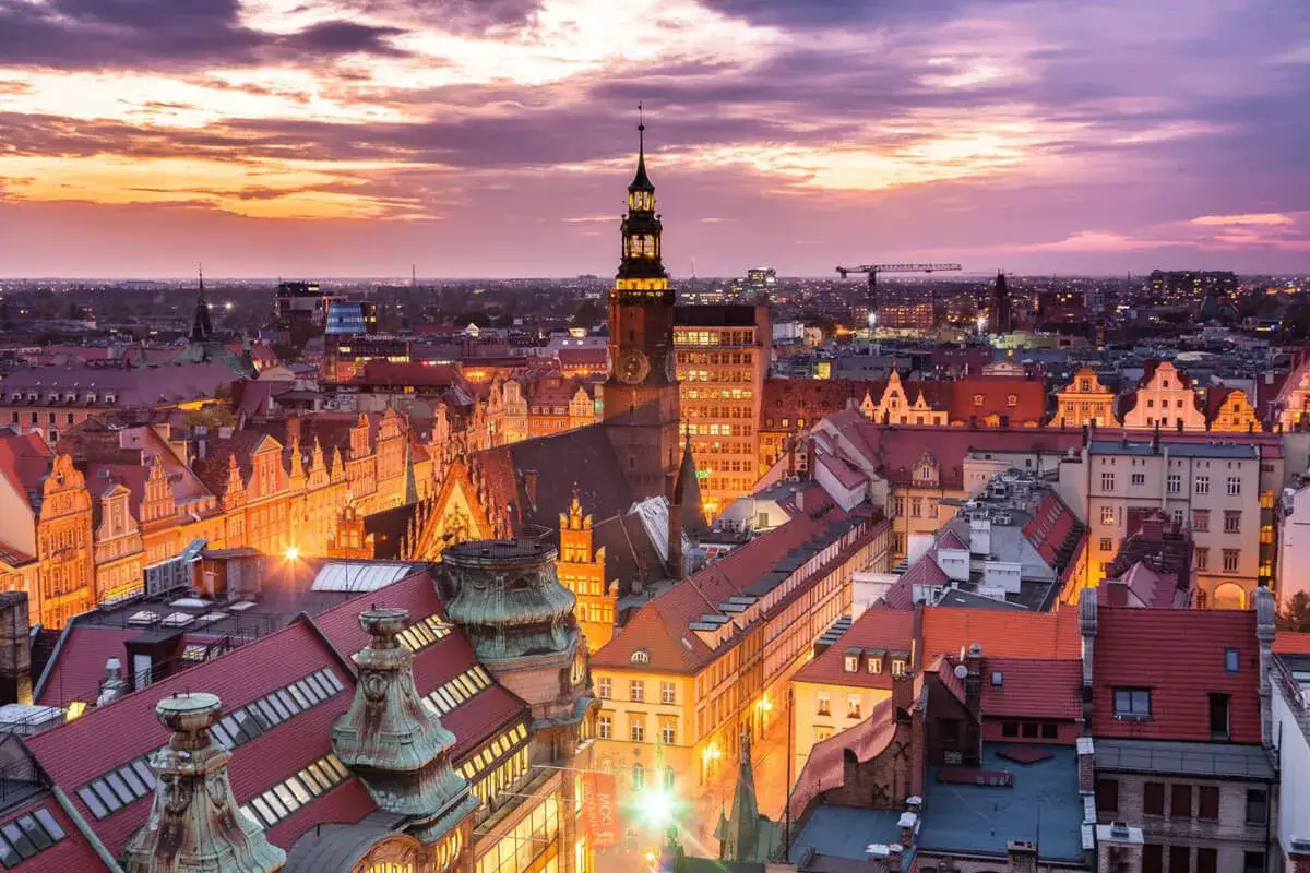 Zachód słońca nad Wrocławiem, największym miastem w Polsce. Widać zabytkowe kamienice i wieżę ratuszową.