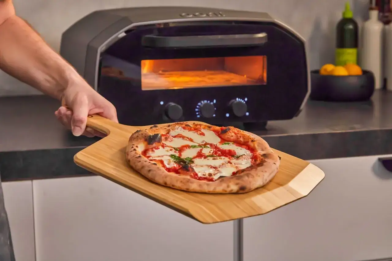 Frisch gebackene Pizza Napoletana mit Mozzarella und Basilikum wird aus einem Pizzaofen genommen.