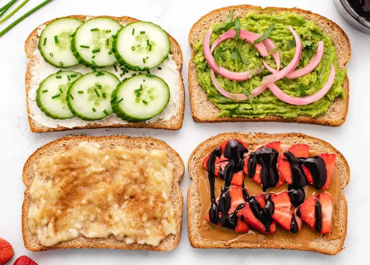 Cuatro tostadas con ingredientes variados: pepino y cebollino, aguacate y cebolla morada, plátano y canela, y fresas con chocolate. ¡Deliciosos desayunos veganos!