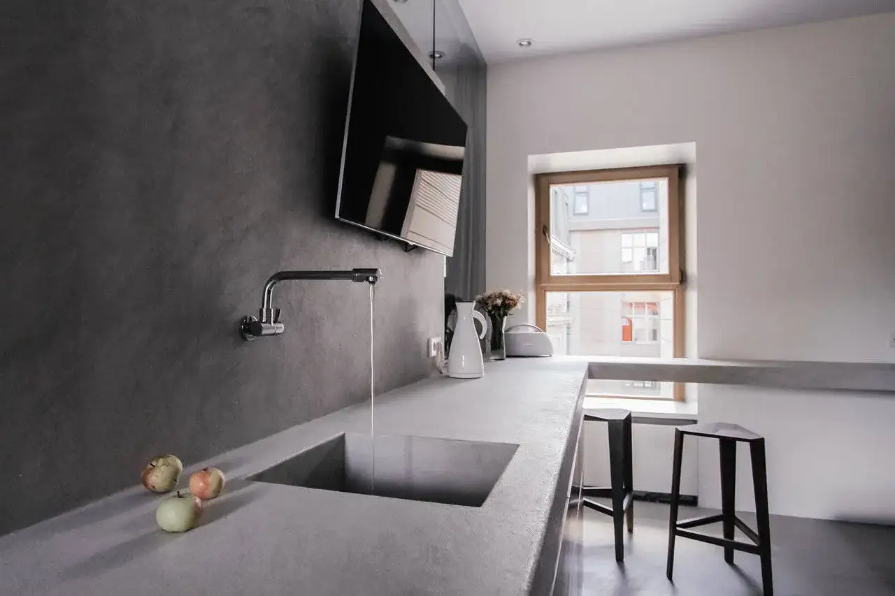 Plan de travail en b&eacute;ton cir&eacute; sur carrelage, avec un &eacute;vier int&eacute;gr&eacute;, un robinet moderne et des pommes.