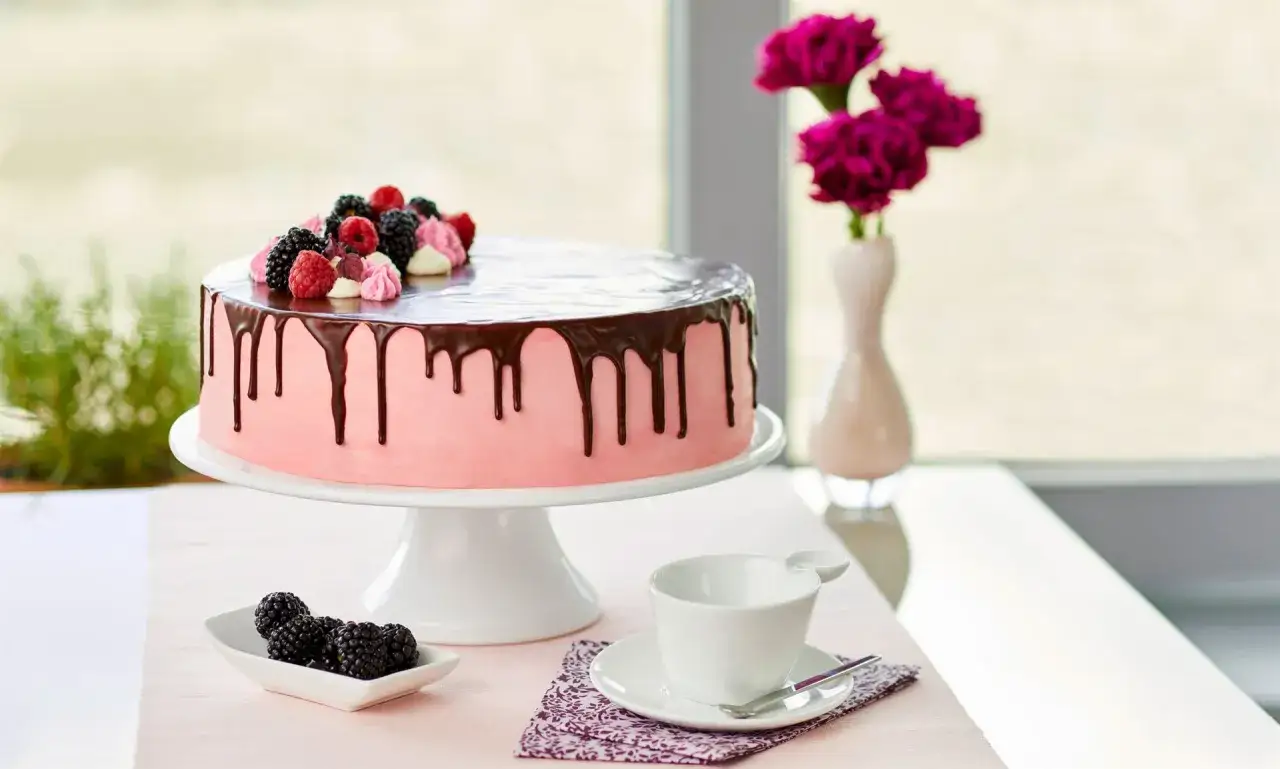 Rosa Torte mit Schokodrip & Beeren, ein Traum f&uuml;r geile Torten Rezepte! Daneben eine Tasse und Beeren.