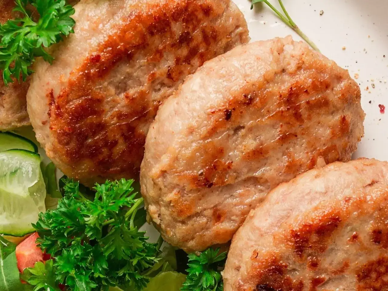 Apetyczne kotlety z indyka, rumiane i soczyste, podane z chrupiącą sałatką z ogórka i natki pietruszki.