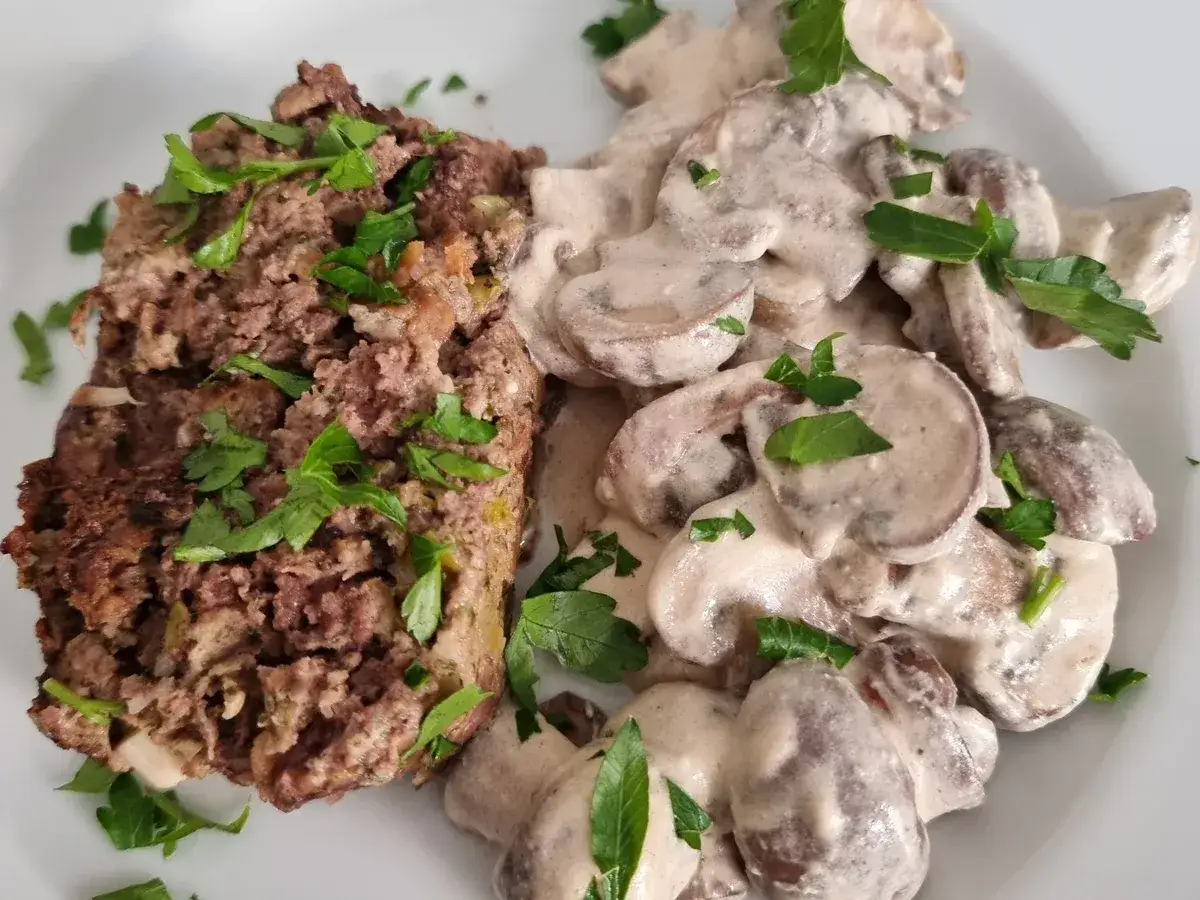 Hackbraten mit cremiger Champignon Rahm Sauce, garniert mit frischer Petersilie.