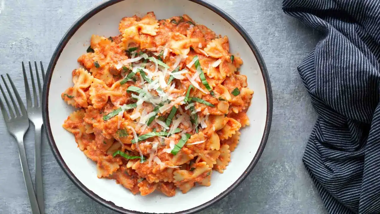 Farfalle Nudeln in cremiger Tomatensoße, garniert mit Basilikum und Parmesan. Ein köstliches Gericht für Ihre Farfalle Rezepte Sammlung.