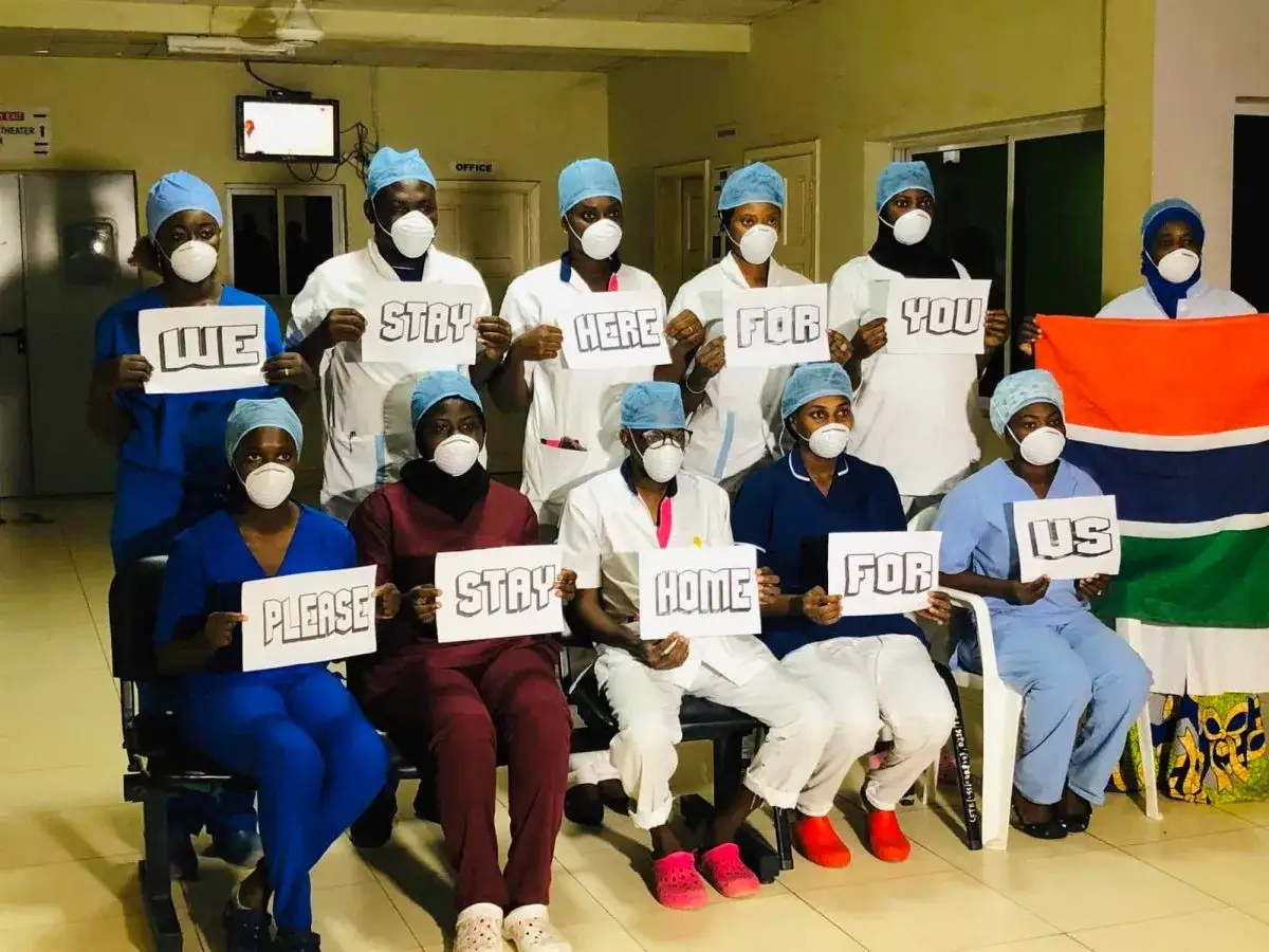 Sjukvårdspersonal i Gambia håller upp skyltar med texten
