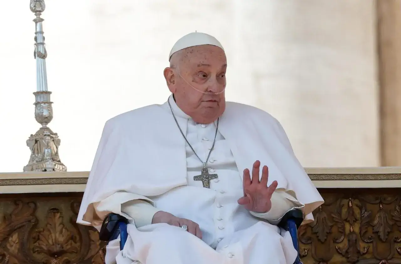 Papież Franciszek w białej szacie, z rurką tlenową, siedzi na wózku, błogosławiąc świat urbi et orbi.