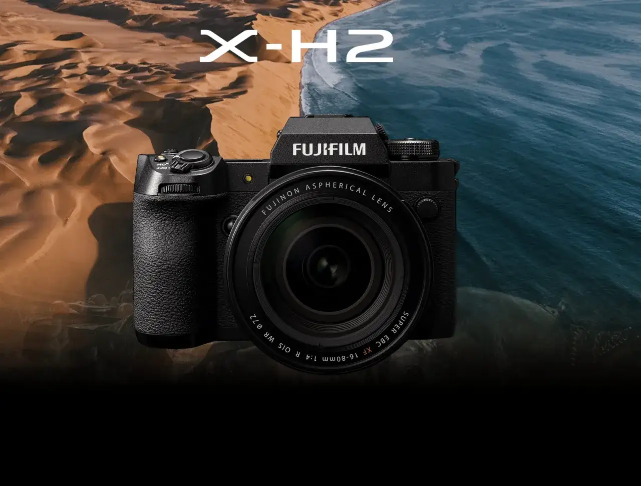 Fujifilm X-H2-kameran framsida med en lins, placerad framför en bakgrund av sanddyner och hav.