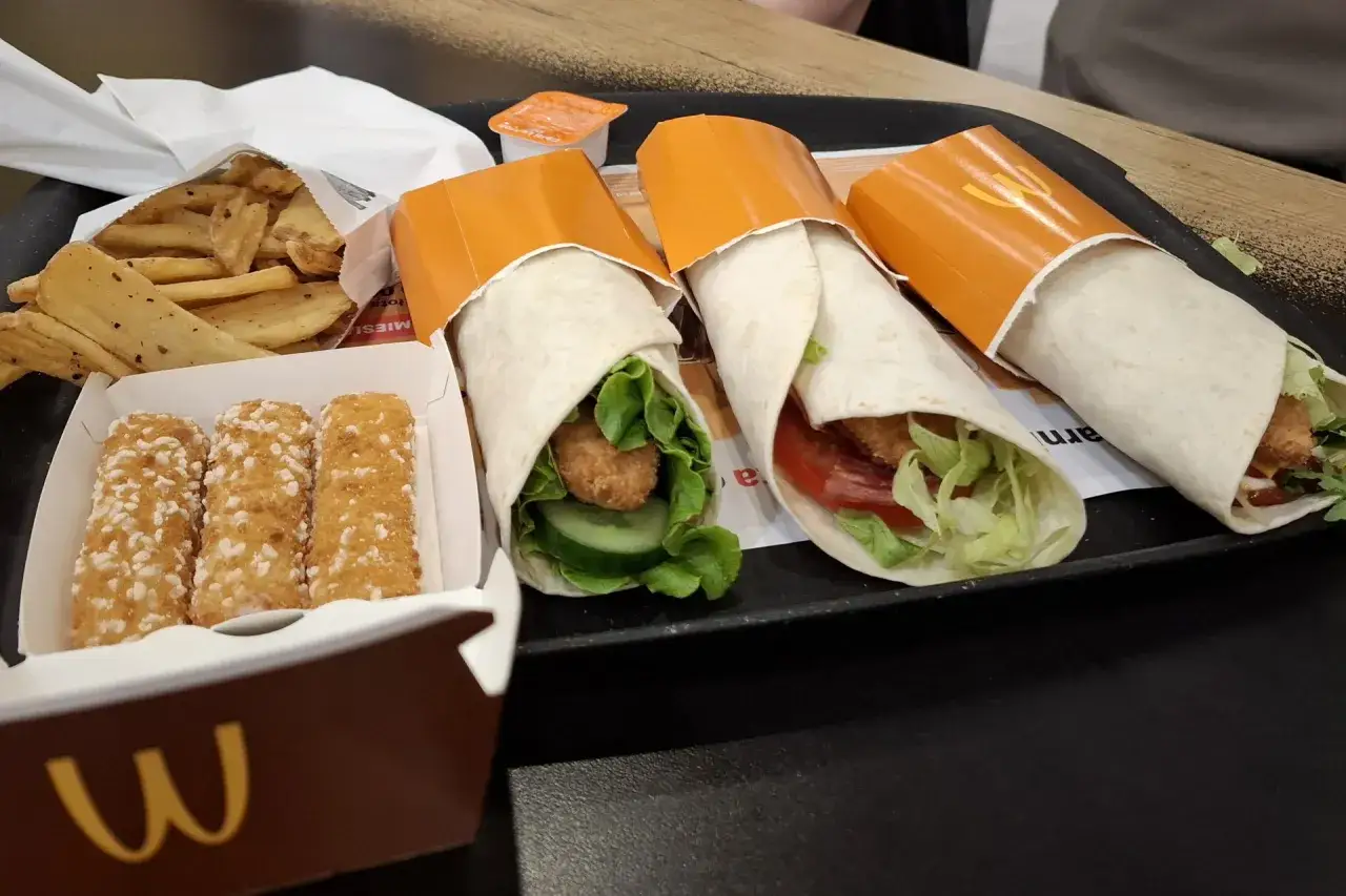Trzy wrapy w pomarańczowych opakowaniach, frytki i paluszki serowe. Zastanawiasz się, ile kosztuje wrap w MC?