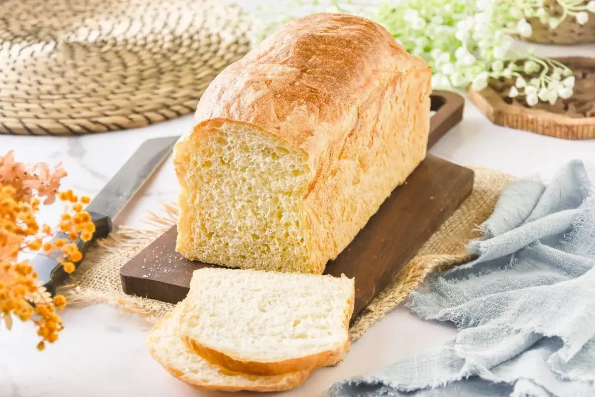 Un pan de patata dorado y esponjoso, reci&eacute;n cortado, sobre una tabla de madera.