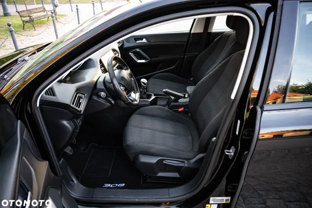 Wnętrze czarnego Peugeot 308 z 2015 roku. Widoczne przednie fotele, deska rozdzielcza i kierownica.