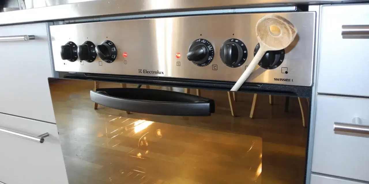 Ein Holzlöffel lehnt am geöffneten Electrolux-Backofen nach dem Backen. Die Innenbeleuchtung ist an.