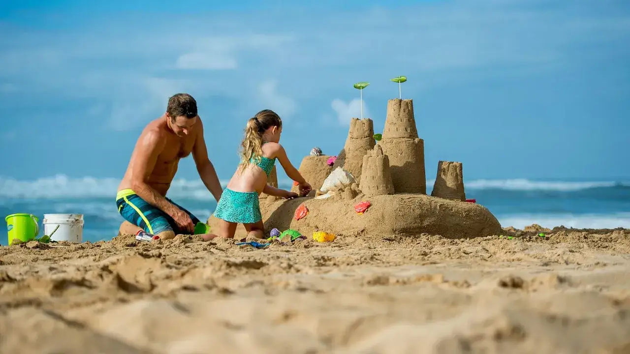 Padre e hija construyen un castillo de arena en la playa. &iexcl;Una idea genial de qu&eacute; hacer en Murcia con ni&ntilde;os!