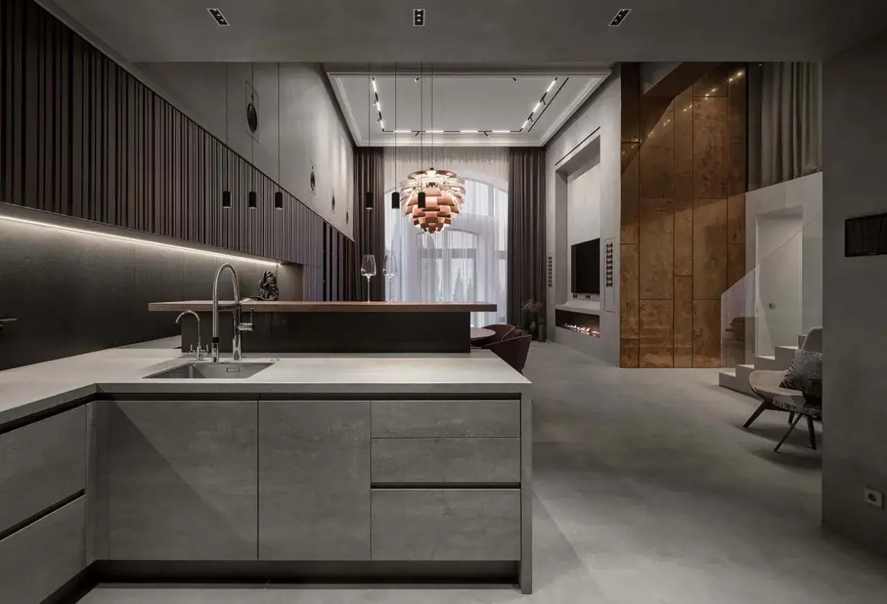 Cocina moderna con encimeras y armarios de microcemento, barra de madera y detalles met&aacute;licos.