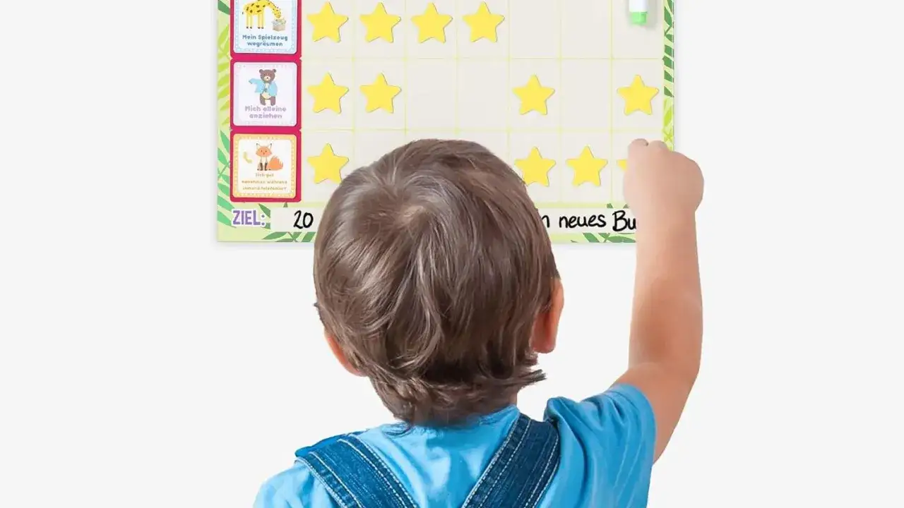 Ein Kind klebt Sterne auf eine Belohnungstafel im Kindergarten. Das Belohnungssystem motiviert zu guten Taten.