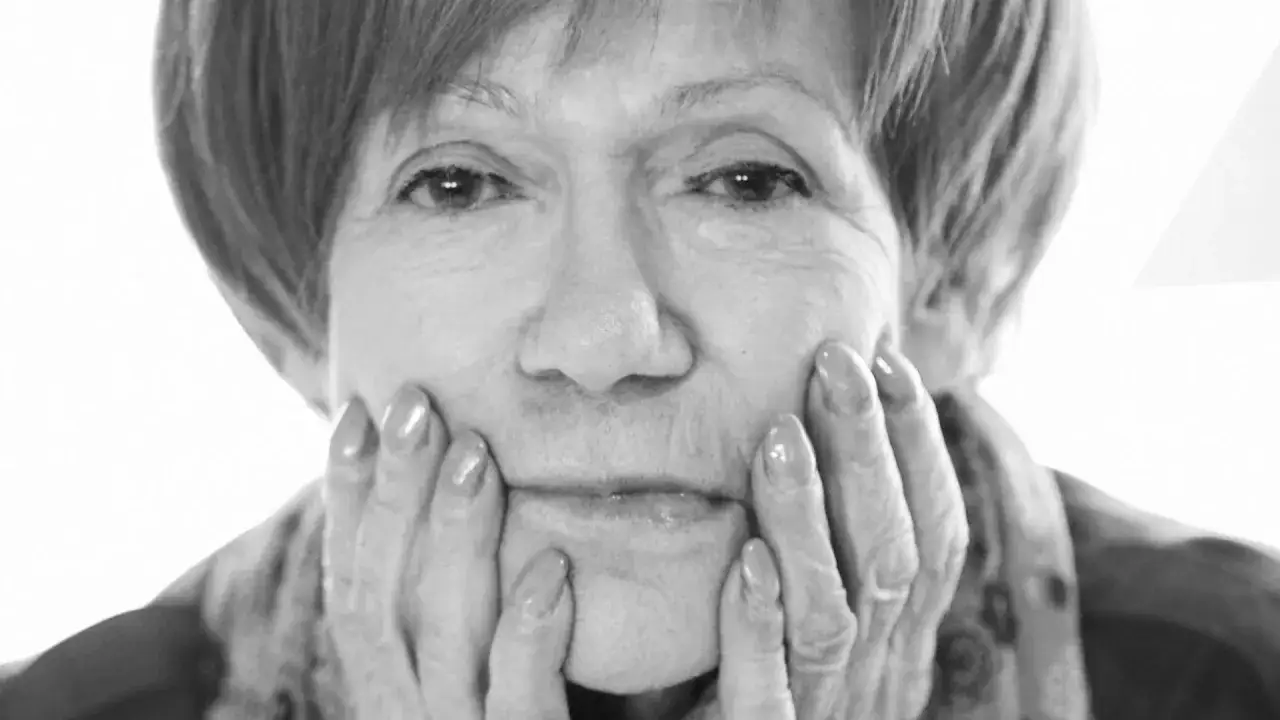 Portret Marii Czubaszek, z dłońmi opartymi o policzki. Jej spojrzenie przywodzi na myśl jej słynne, błyskotliwe maria czubaszek cytaty.