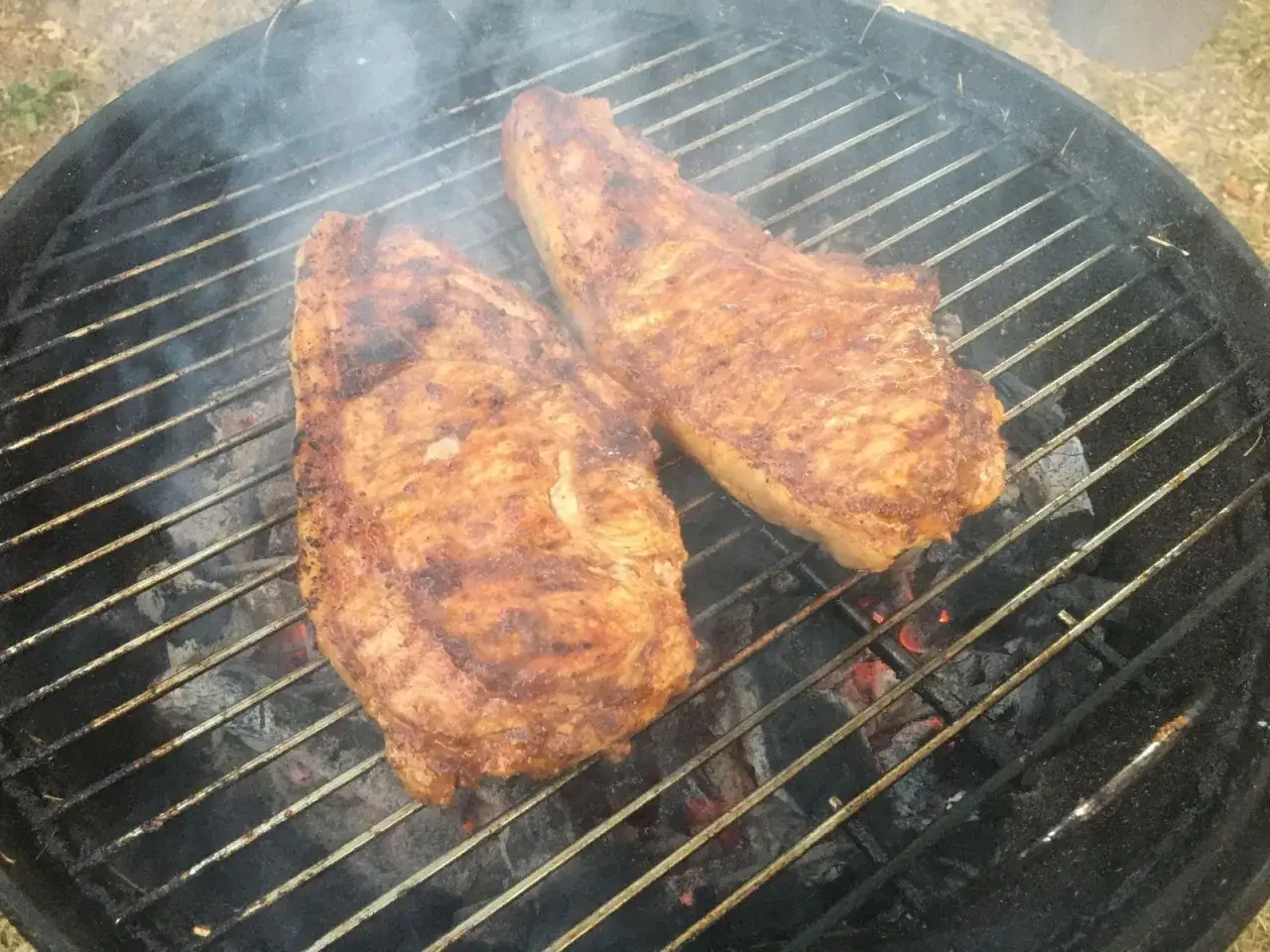 Deux belles c&ocirc;tes de veau barbecue gr&eacute;sillent sur le grill, d&eacute;gageant une fum&eacute;e all&eacute;chante.